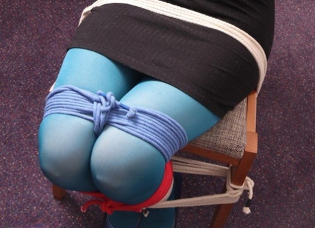 White girl with cinnamon hair is tied to a chair in a dark dress and blue hose 81730052