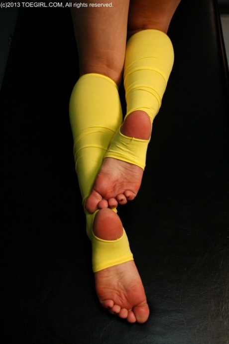 Caucasian female plays with her feet while wearing yellow leg warmers 94942296