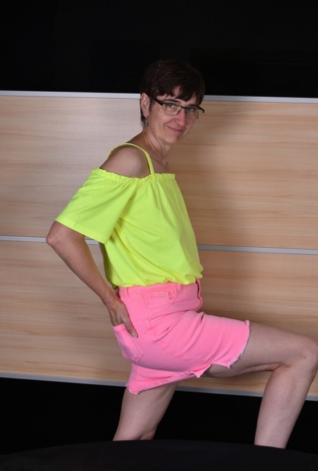 Mature woman undoes the snap and zipper on a pink miniskirt during SFW action 33282194